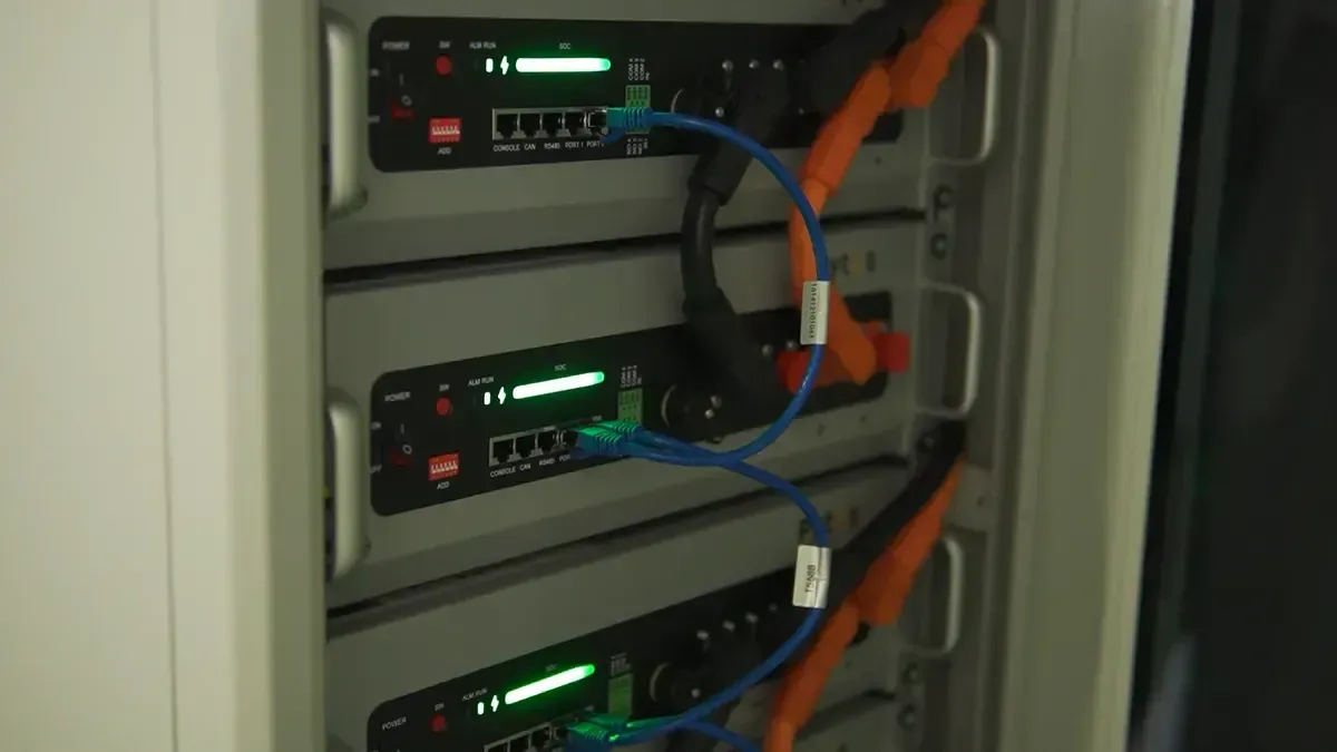 Na zdjęciu znajdują się moduły baterii litowych zamontowane na ścianie w pomieszczeniu technicznym, obok falownika, co sugeruje zastosowanie w systemie magazynowania energii elektrycznej w ramach instalacji fotowoltaicznej. Te nowoczesne urządzenia mają na celu zwiększenie efektywności wykorzystania odnawialnych źródeł energii.